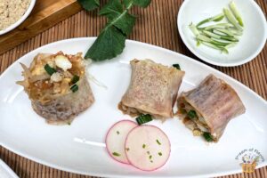 Singapore popiah recipe on a white plate with two radish slices