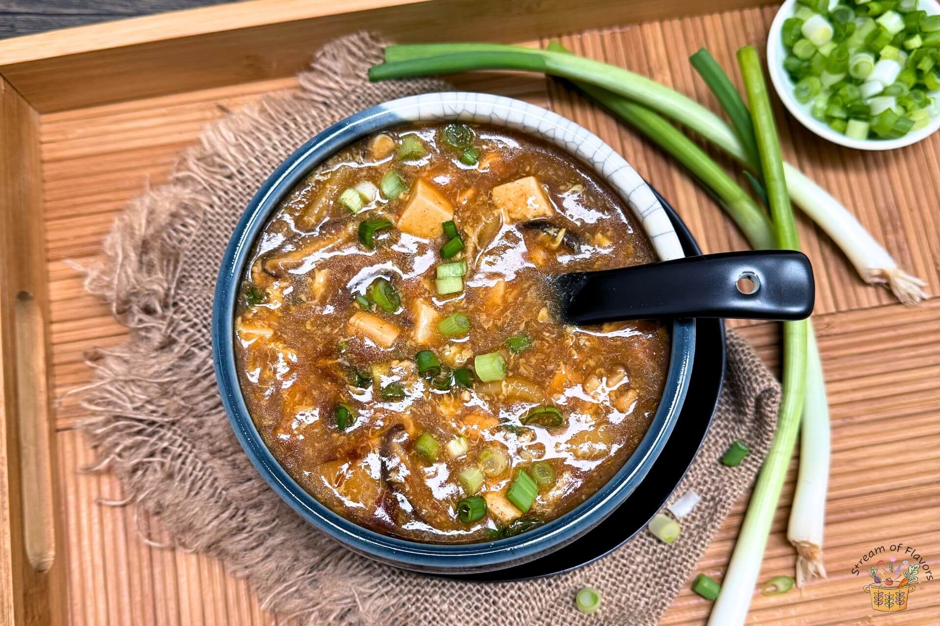 chicken hot and sour soup in a blue bowl with scallions