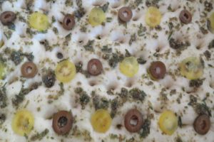 Top the focaccia bread with olives and cherry tomatoes
