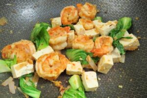 bok choy with shrimp and tofu in a wok