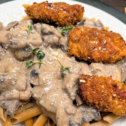 healthy cajun chicken pasta with bella mushrooms in a white plate