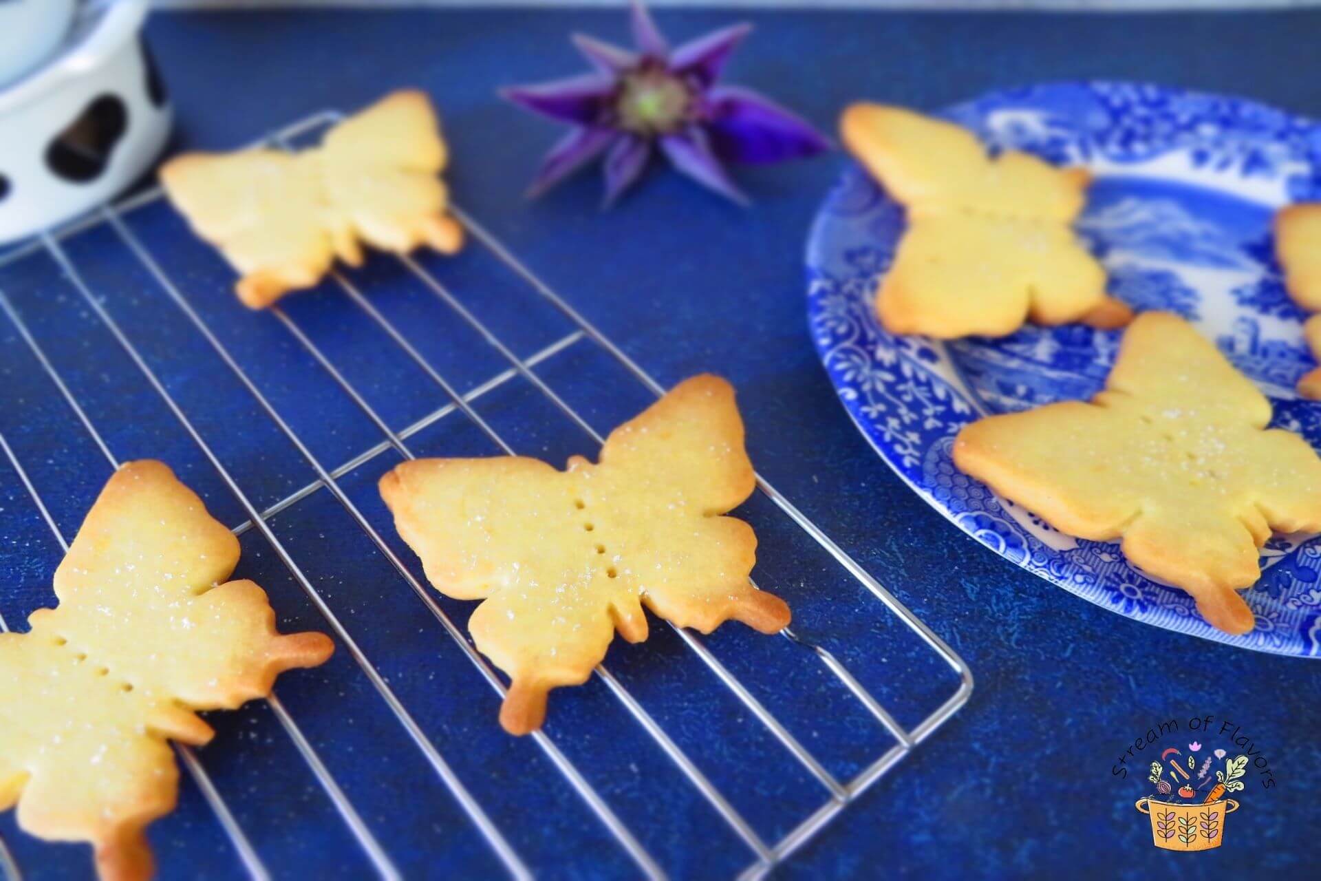 Butterfly-shaped Shortbread cookies placed on a wire rack and blue plate on a blue base