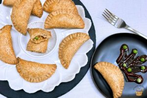 baked chicken empanadas on white and black plates