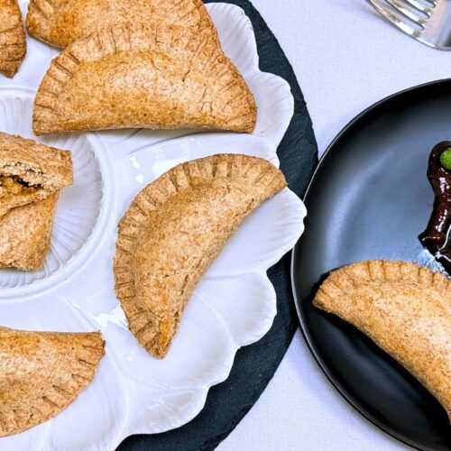 baked chicken empanadas on a white and black plate