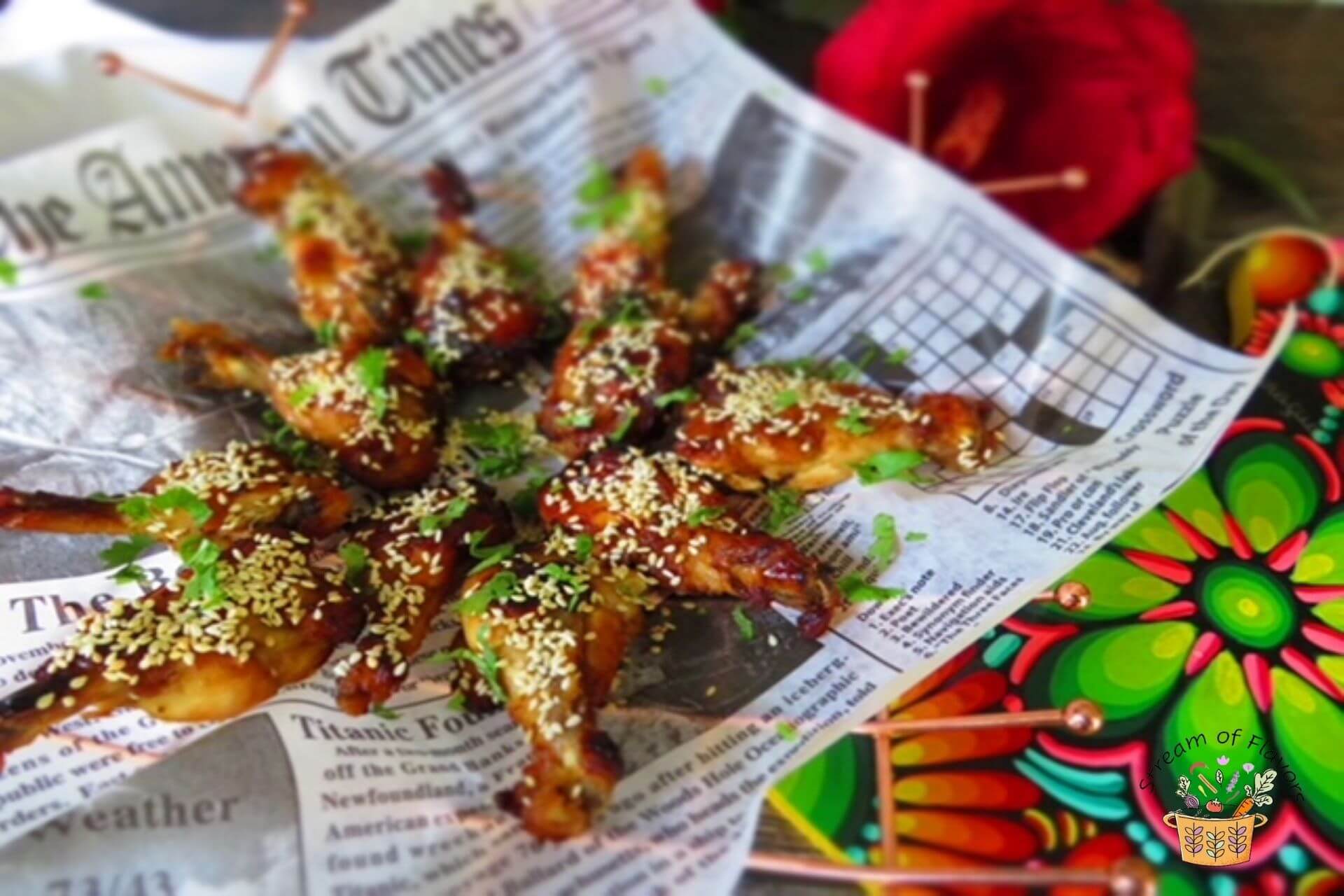 Spicy chicken wings topped with sesame seeds arranged on a newspaper placed on top of a copper rack
