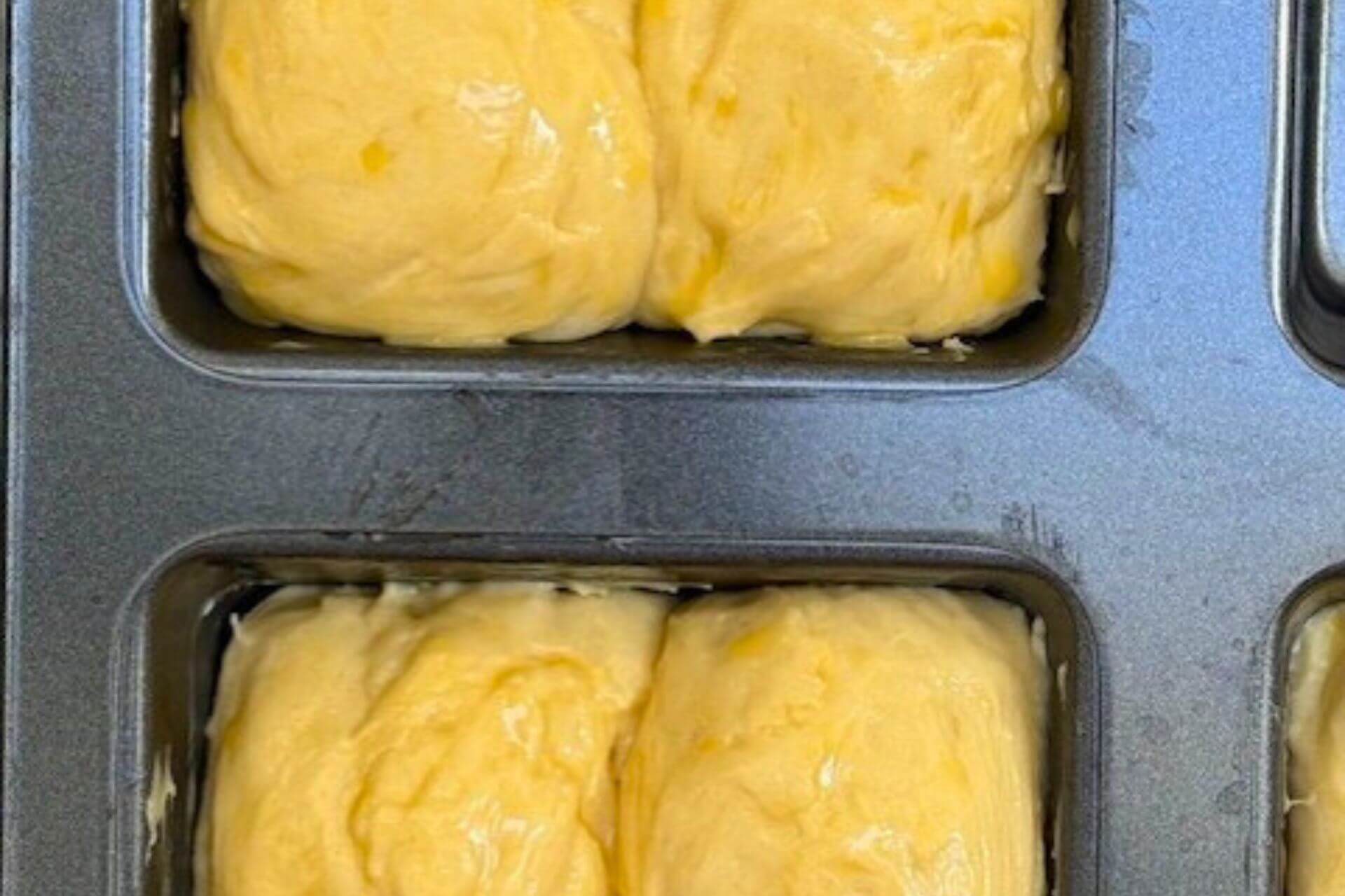 mini loaves shaped and brushed with egg wash in a loaf tray