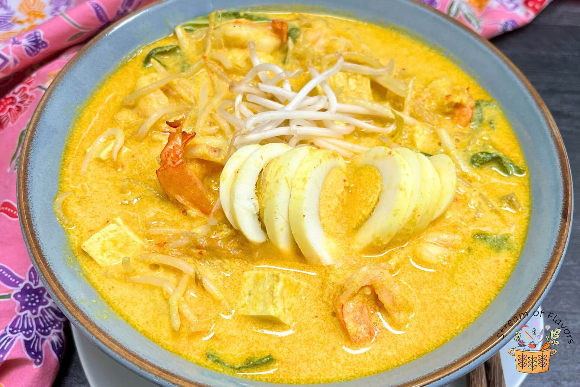 laksa lemak with a boiled egg in a blue bowl