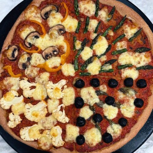 four seasons pizza on a black pizza stone
