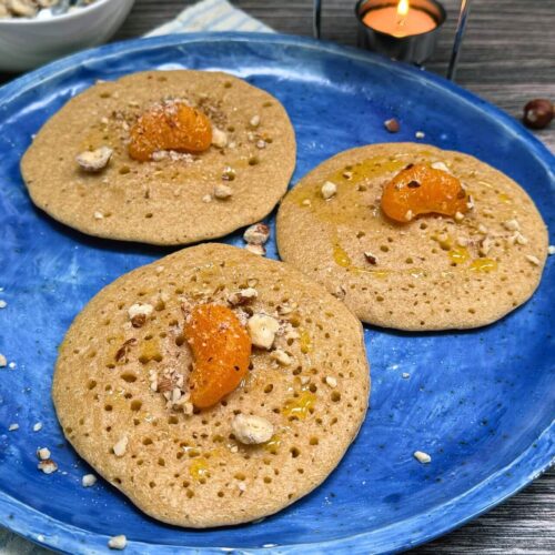 Moroccan semolina pancakes with orange segments and sauce in a blue plate