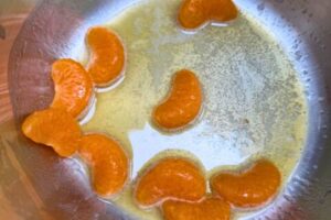 orange segments in a pot with honey