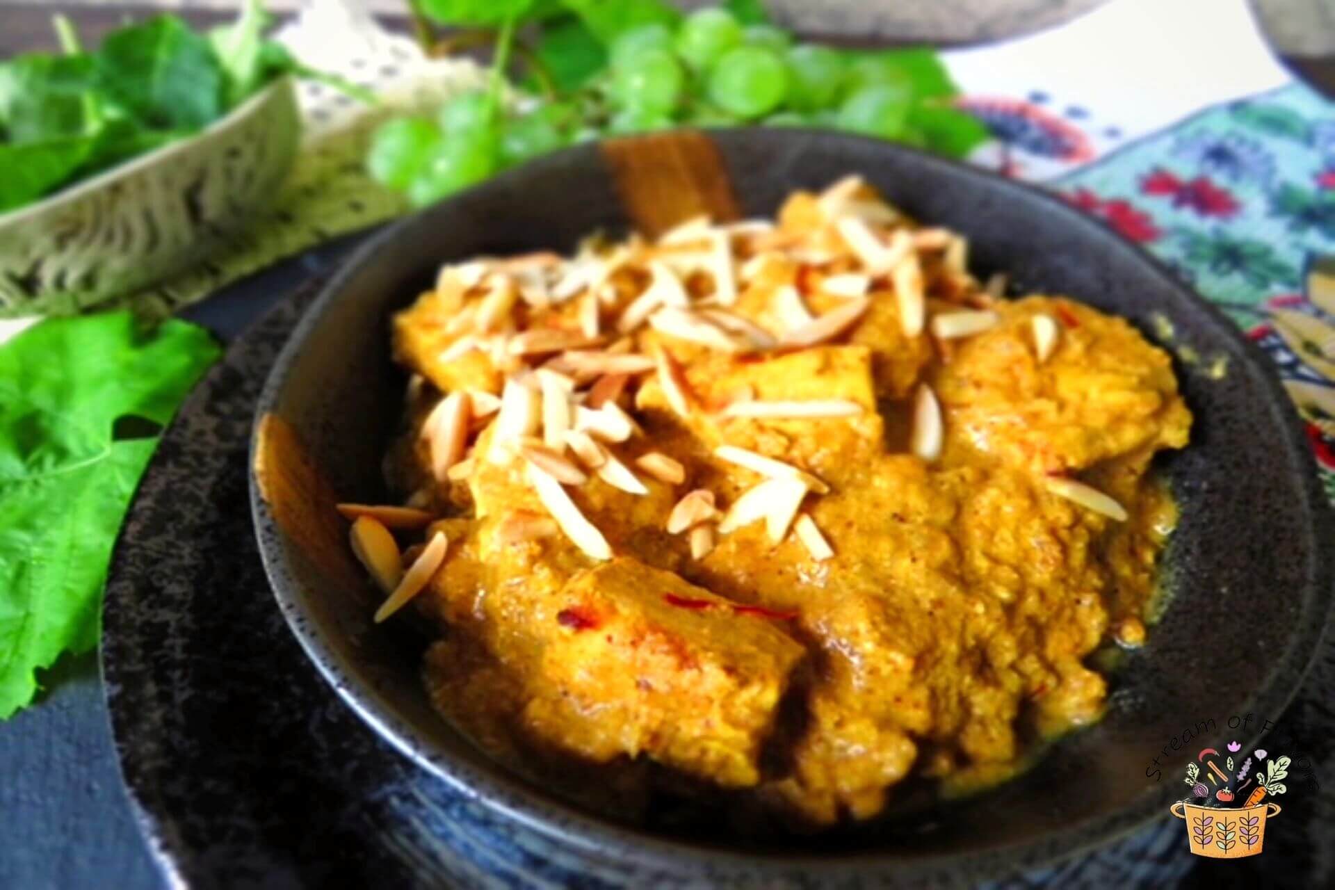 chicken pasanda in a bowl with almond slivers on top