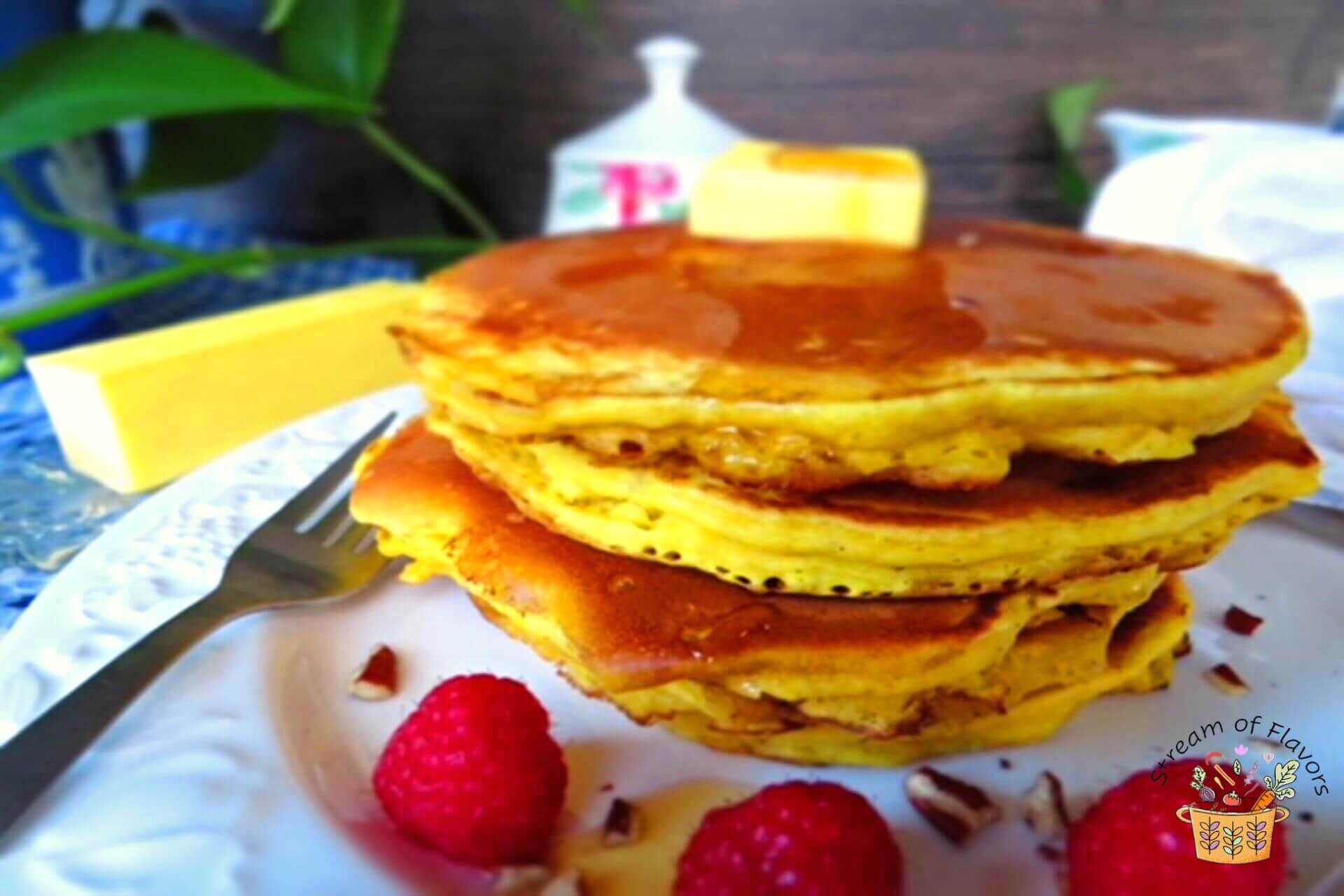 healthy pumpkin pancakes on a plate with raspberries and pecans