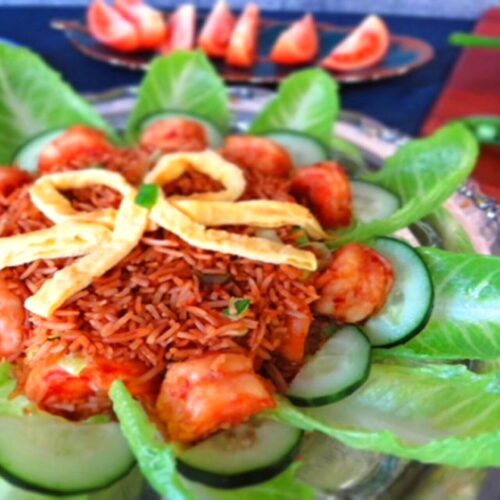 nasi goreng garnished with egg strips and cucumber and prawns on the sides