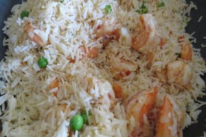 rice added to the prawns in a wok with peas