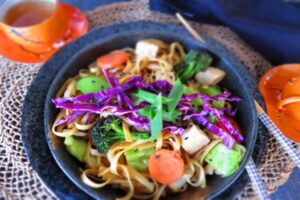 garnish the vegetable chow mein with scallion, red cabbage and sesame seeds