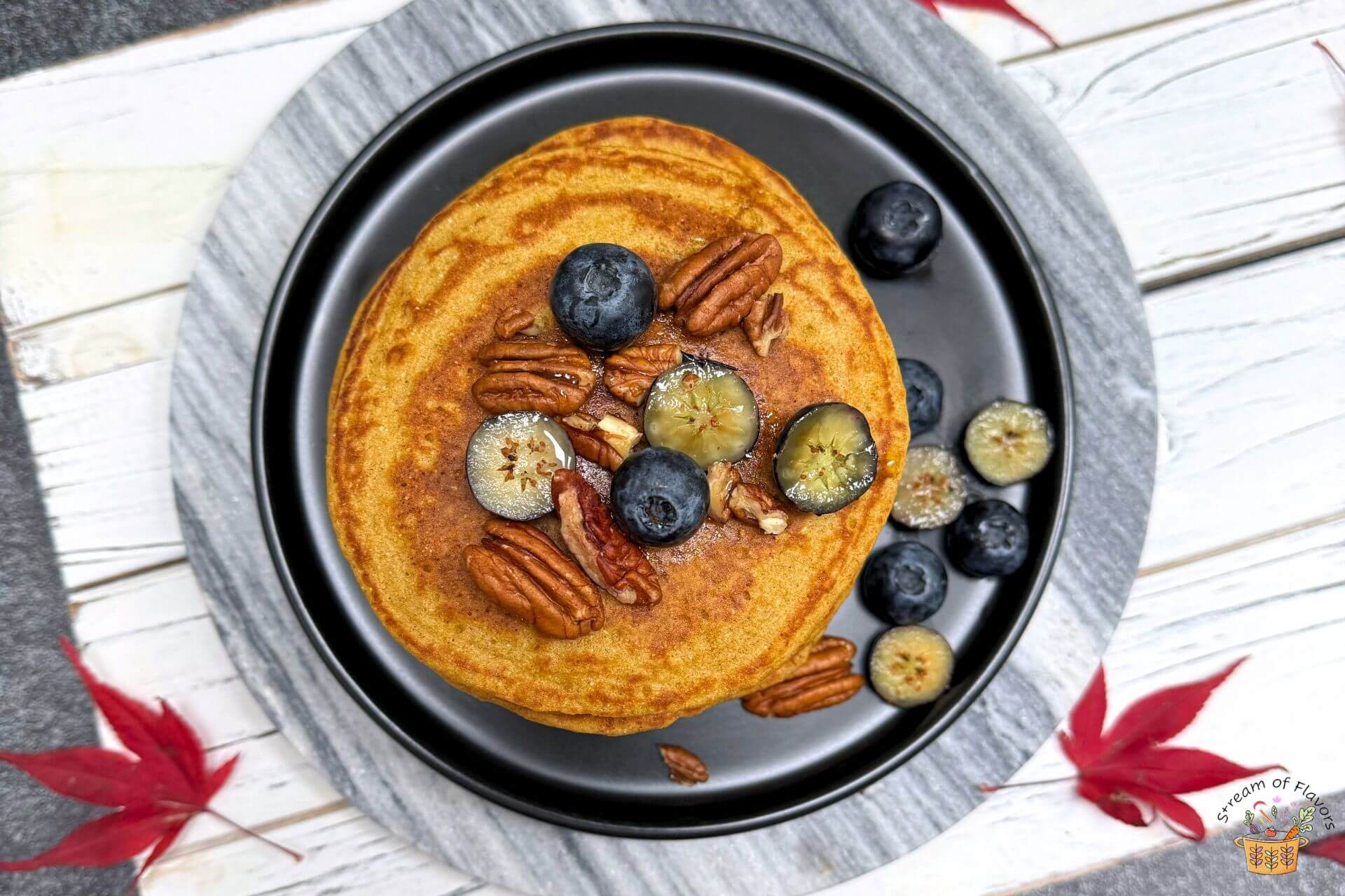 whole wheat pumpkin pancakes in a black plate with pecans