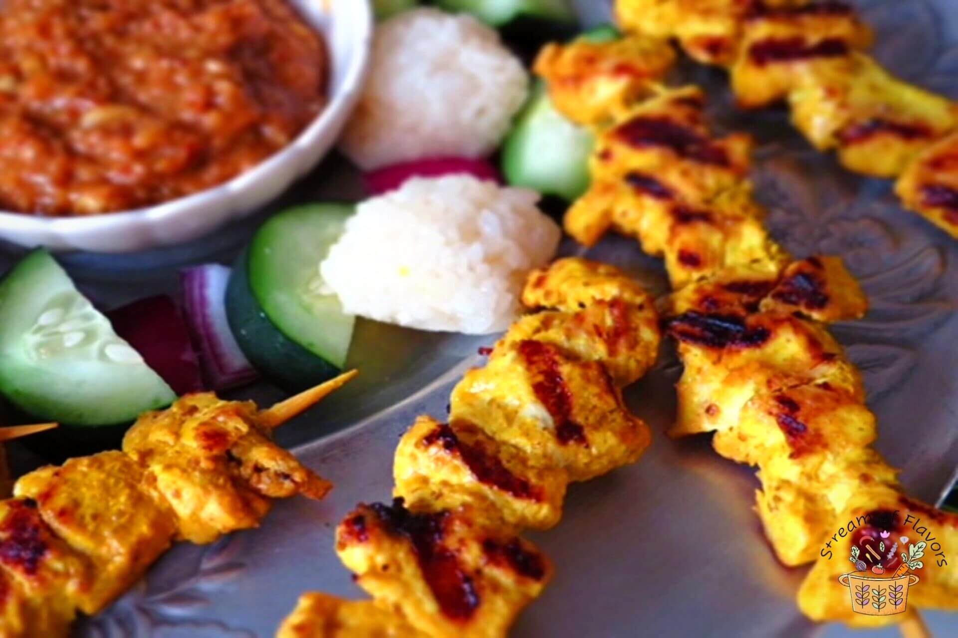 Malaysian chicken satay on a plate with cucumber and katupat