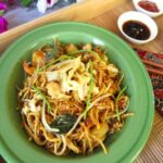 mamak mee goreng recipe in a green bowl on a wooden tray