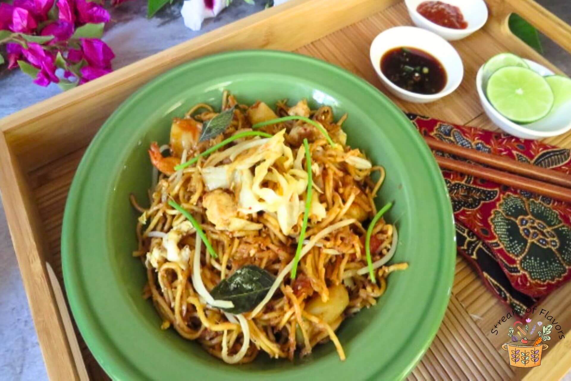 mamak mee goreng recipe in a green bowl on a wooden tray