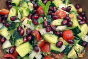 shirazi salad in a wooden bowl with pomegranate