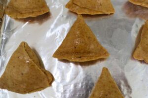 samosa brushed with oil on foil lined baking tray