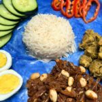 Nasi lemak recipe with ikan sambal and chicken rendang on a blue plate