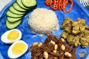 Nasi lemak recipe with ikan sambal and chicken rendang on a blue plate