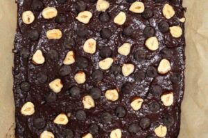 avocado brownie batter with chocolate chips and hazelnuts in a baking tray