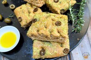 whole wheat focaccia with olives on a black tray