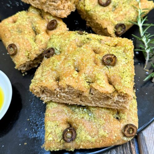 whole wheat focaccia with olives on a black tray