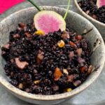 fried black rice with watermelon radish slice in a gray bowl