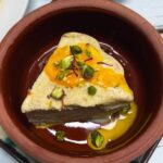 kesar pista kulfi slice in a clay bowl with pistachio on top
