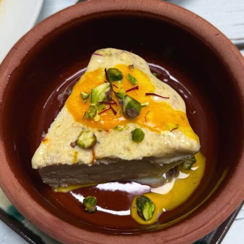 kesar pista kulfi slice in a clay bowl with pistachio on top