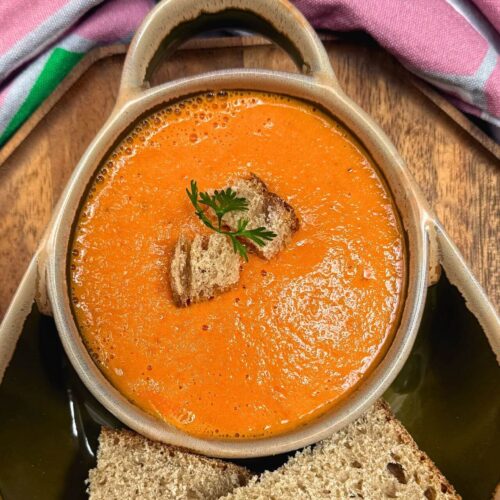Indian tomato soup in a green bowl with croutons