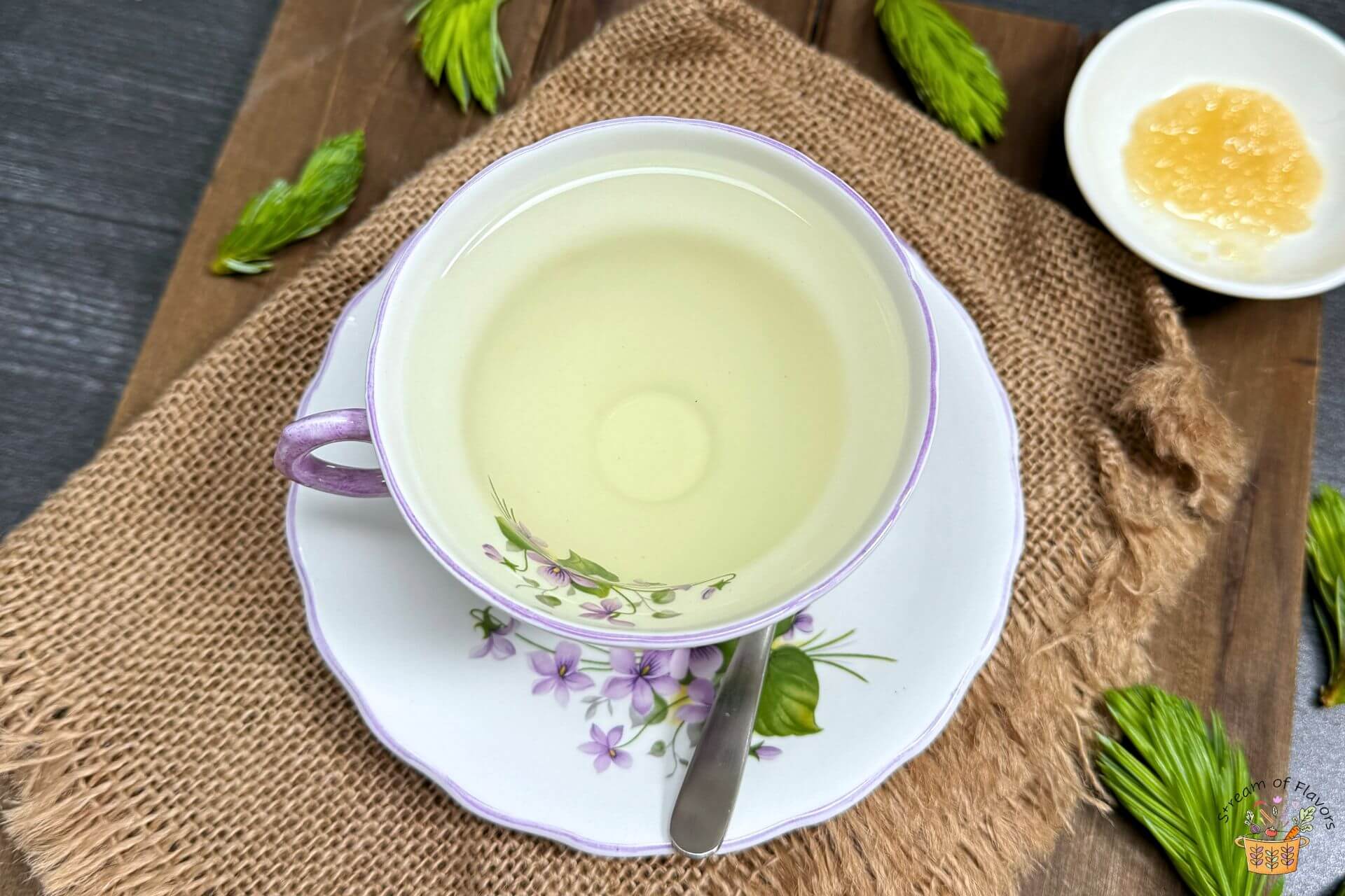 spruce tea in a white cup with honey on the side