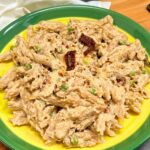 garlic cauliflower pasta in a yellow green plate with sundried tomato and peas