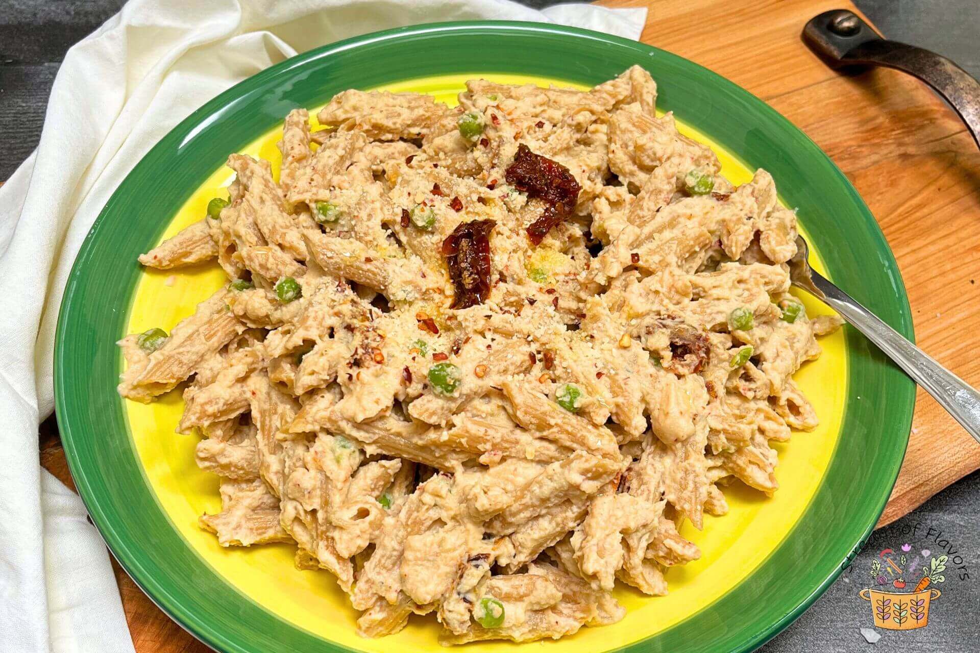 garlic cauliflower pasta in a yellow green plate with sundried tomato and peas