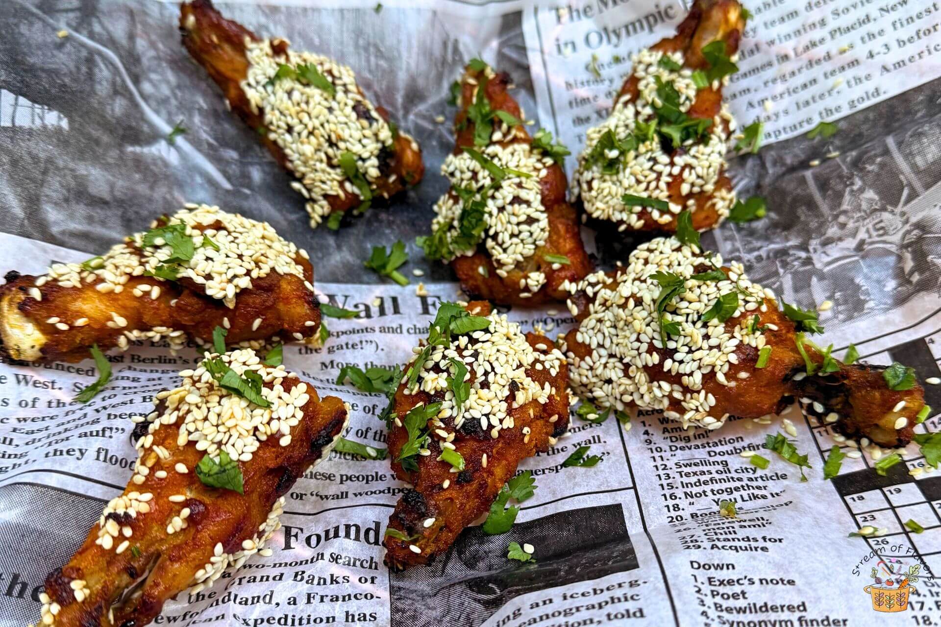 Honey-Glazed Chicken Wings with sesame seeds on a newspaper print garnished with cilantro