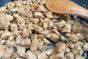 chciken added to the spice paste in a wok