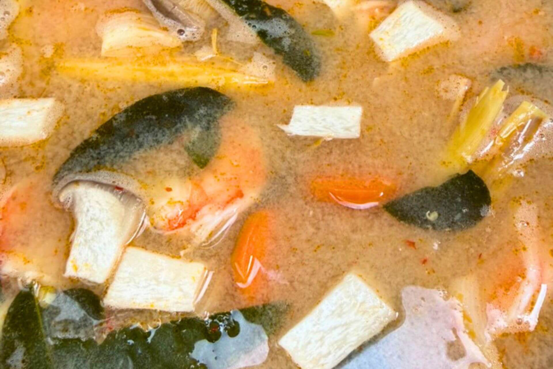 shrimp stock with aromatics, carrots, shrimp and kaffir lime leaves